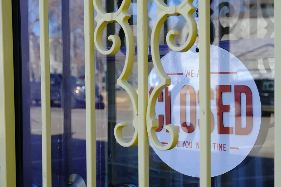 closed sign on glass door behing bars